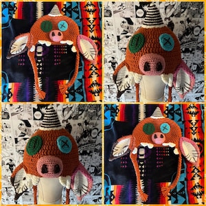 May include: A crocheted hat shaped like a monster with brown, green, and pink details. The hat has long, dangling strings and a wide brim.