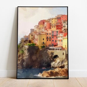 May include: A watercolor painting of a colorful village built on a cliff overlooking the ocean. The buildings are painted in shades of yellow, orange, red, and pink. The ocean is a deep blue, and the sky is a soft pink.