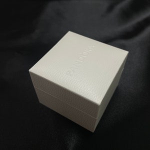 May include: A white square box with the word "PANDORA" embossed on the top.
