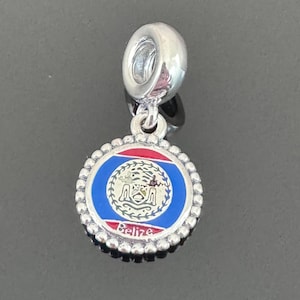 Pode incluir: Berloque de prata com um design de esmalte azul, vermelho e branco da bandeira de Belize. O berloque tem um laço de prata para prender a uma pulseira ou colar. O berloque apresenta o texto "Belize" na parte inferior.