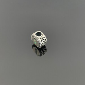 May include: Silver charm with a heart-shaped cutout and a patterned design. The charm has a small inscription that reads "925 ALE".