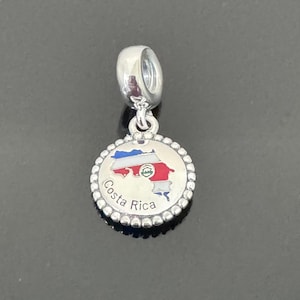 May include: Silver charm with a red, white, and blue enamel map of Costa Rica. The charm has a beaded border and a loop for attaching to a bracelet.