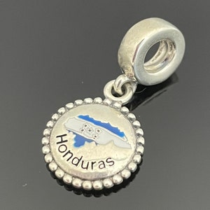 May include: Silver charm with a blue and white enamel outline of Honduras and the word "Honduras" in black lettering.