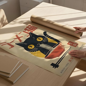 May include: A beige poster featuring a black cat eating ramen from a red bowl, with Japanese text. The poster is on a wooden table, next to a rolled-up brown paper tube and several beige notebooks. The poster's theme is related to food and cats.