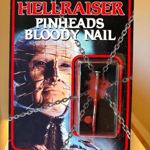 May include: A Hellraiser Pinheads Bloody Nail collectible in original packaging. The card features an image of Pinhead, the text HELLRAISER PINHEADS BLOODY NAIL, and a metal nail with red paint inside a plastic blister pack, wrapped in a metal chain.