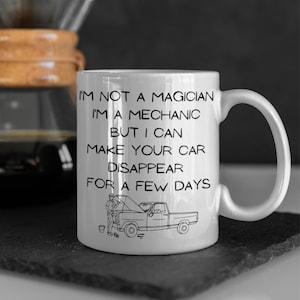 May include: White ceramic coffee mug with a black outline of a pickup truck and a mechanic. The mug reads "I'm not a magician, I'm a mechanic, but I can make your car disappear for a few days."