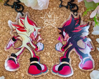 May include: Two acrylic keychains featuring a stylized character in a dynamic pose. One keychain displays the character in cream and red, while the other shows the character in black and red. Both include black star-shaped clasps and the text dokilbi.