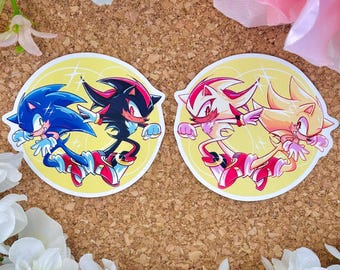 Könnte beinhalten: Zwei runde Aufkleber mit den Charakteren Sonic the Hedgehog und Shadow the Hedgehog. Die Aufkleber sind gelb mit einem weißen Rand und zeigen die Charaktere in einer dynamischen Pose. Die Charaktere sind im Cartoon-Stil mit leuchtenden Farben gezeichnet.