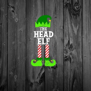 May include: Green elf hat with a white "THE HEAD ELF" text and red and white striped legs. The elf is wearing green shoes with a yellow buckle.