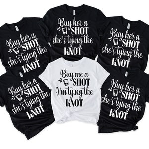 Könnte beinhalten: Fünf schwarze und weiße T-Shirts mit einem Shotglas-Motiv und dem Text "Buy her a shot she's tying the knot" oder "Buy me a shot I'm tying the knot".