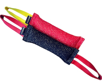 May include: Two dog chew toys with red and black fabric and yellow and red straps. The straps have the text "ADZK9S" printed on them.