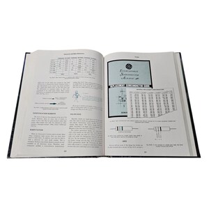 May include: An open book with black covers, displaying pages filled with text, diagrams, and charts. The right page features a blue and white "Entertainment Semiconductor Almanac" guide. The book is likely related to electronics and semiconductors.