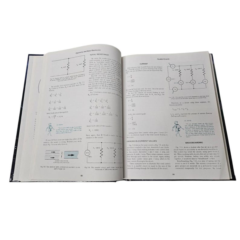 May include: An open textbook on a white surface, featuring diagrams and equations related to electricity and basic electronics. The pages display text and illustrations of circuits and electrical components.