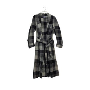 May include: A long-sleeved robe featuring a black, gray, and white plaid pattern. The garment includes a wide shawl collar, a matching tie belt at the waist, and folded cuffs on the sleeves. It is displayed on a white plastic hanger.