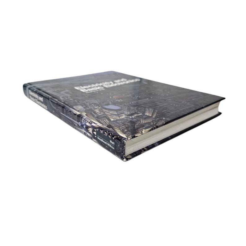 May include: A hardcover book titled "Electricity and Basic Electronics" with a cityscape design on the cover. The book has white-edged pages and appears to be in good condition. The author's name is visible at the bottom.