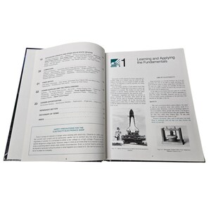May include: An open book with black and white text and illustrations. The left page has a table of contents, and the right page has the title "Learning and Applying the Fundamentals" with images of a rocket and a device.