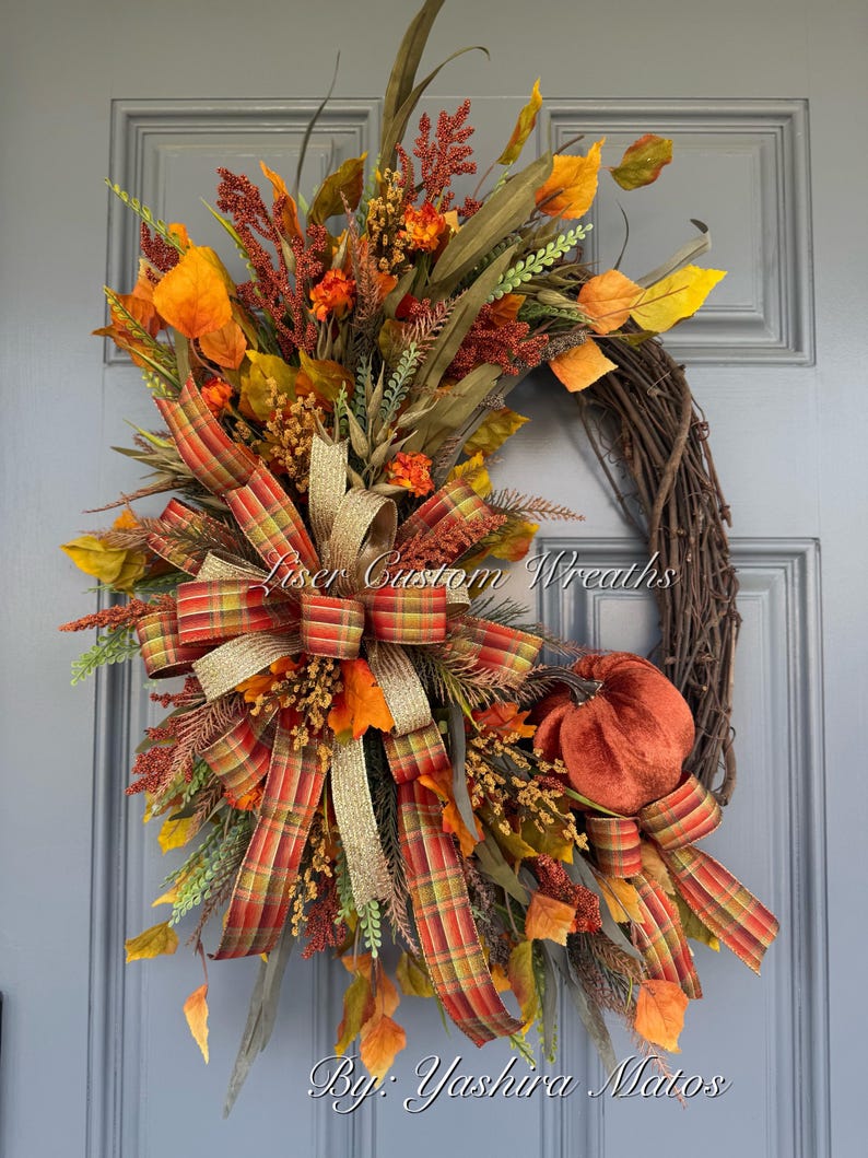 Handmade fall grapevine wreath with orange plaid and gold ribbon, velvet pumpkin, and autumn foliage.