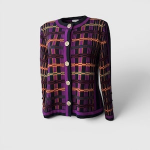 May include: A patterned cardigan in shades of purple, black, orange, and green. The sweater has a round neckline, long sleeves, and gold-coloured buttons. The trim is black and purple.