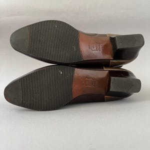 May include: A pair of brown leather shoes with a low block heel and a ribbed rubber forefoot sole. The soles feature a stamped leather centre with the text "SOLE LEATHER" and the size "38" visible on the arch area of each shoe.