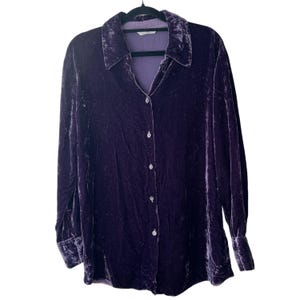May include: A long-sleeved button-down shirt crafted from deep purple crushed velvet fabric. The garment features a classic pointed collar, a full-length front button placket with matching buttons, and buttoned cuffs at the end of each sleeve.