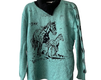May include: A long-sleeve sweater in a speckled mint green color featuring a black turtleneck collar. The front displays a black knit graphic of a horse and a foal standing together. The sleeves have a repeating black teardrop pattern along the side.