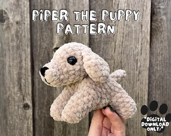 May include: A crocheted beige puppy toy with black eyes and a black nose. The toy is being held in a hand against a wooden background. The text "PIPER THE PUPPY PATTERN *DIGITAL DOWNLOAD ONLY*" is visible in the image.