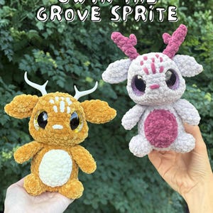 Op de afbeelding: Twee gehaakte pluche wezens getiteld Gwyn the Grove Sprite. De ene is goudbruin met witte geweien en een witte buik. De andere is lichtgrijs met donkerroze geweien, markeringen en een buik. Beide hebben grote, donkere, glinsterende ogen.