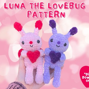 May include: Two crocheted bunny dolls, one pink and one purple, each holding a heart. The dolls have black eyes and red accents. Text at the top reads "LUNA THE LOVEBUG PATTERN". A heart graphic with "*DIGITAL DOWNLOAD ONLY*" is in the lower right.