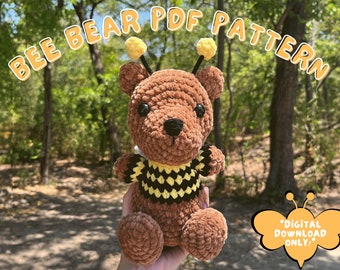 Peut inclure: Un ourson en peluche crocheté en forme d'abeille avec une fourrure brune, des ailes rayées noires et jaunes et un pull rayé jaune et noir. Le jouet est tenu dans une main sur un fond flou d'arbres. Le texte "BEE BEAR PDF PATTERN" est écrit en lettres jaunes en haut de l'image. Le texte "DIGITAL DOWNLOAD ONLY" est écrit en lettres jaunes sur une forme d'aile d'abeille jaune et noire en bas de l'image.