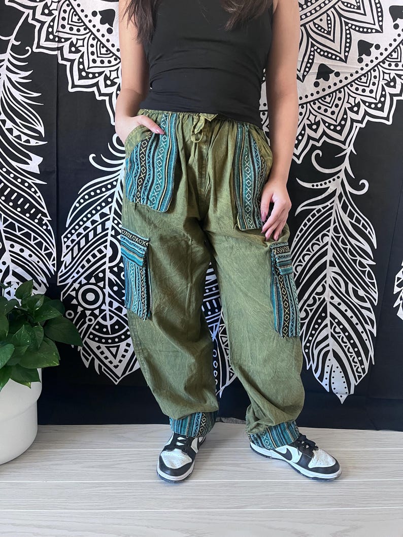 May include: Green cargo pants with blue and white patterned trim around the pockets and cuffs. The pants have a drawstring waist and are made of a soft, comfortable fabric.