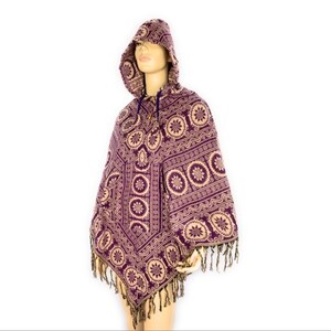 K&ouml;nnte beinhalten: Lila und beigefarbener Kapuzenponcho mit geometrischem Muster und Fransenbesatz.