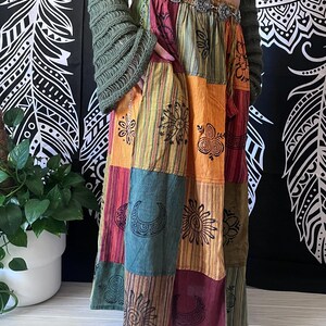 Puede incluir: Una falda larga de patchwork multicolor con una variedad de dise&ntilde;os impresos, incluyendo soles, lunas y remolinos. La falda est&aacute; hecha de algod&oacute;n y tiene un ajuste holgado.