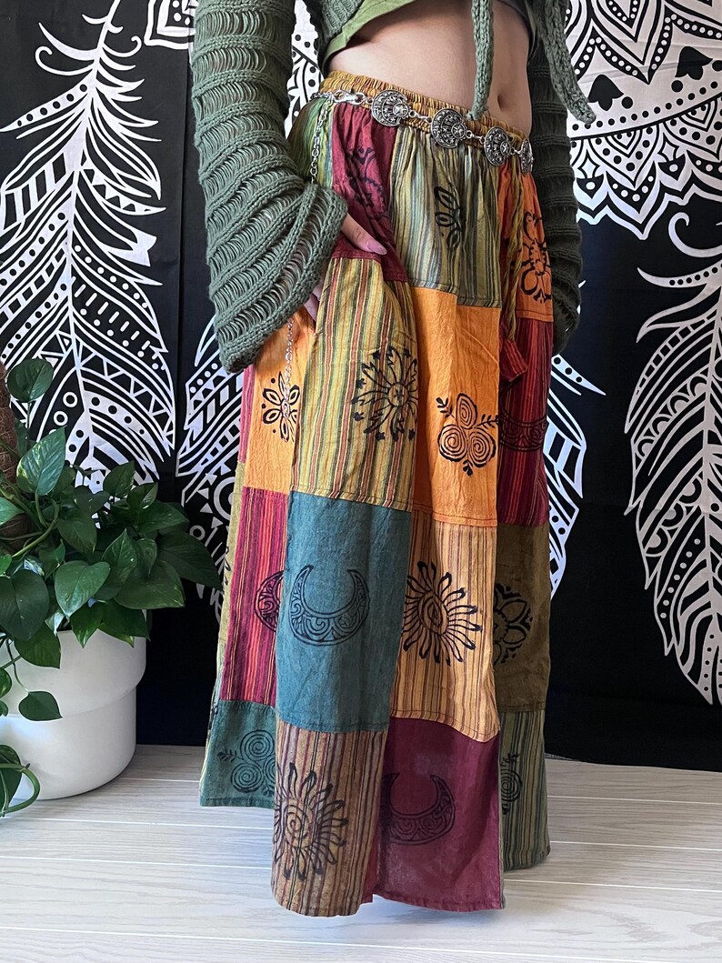 Puede incluir: Una falda larga de patchwork multicolor con una variedad de dise&ntilde;os impresos, incluyendo soles, lunas y remolinos. La falda est&aacute; hecha de algod&oacute;n y tiene un ajuste holgado.