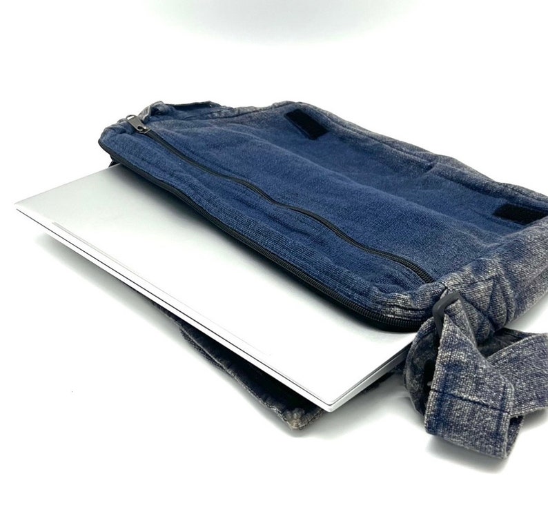 Może przedstawiać: Niebieska torba na laptopa z denimu z zamkiem błyskawicznym i paskiem na ramię. Torba jest otwarta, a w środku znajduje się srebrny laptop.
