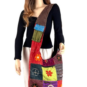 Puede incluir: Un bolso de hombro de patchwork multicolor con flores bordadas. El bolso está hecho de diferentes telas y tiene una correa marrón.
