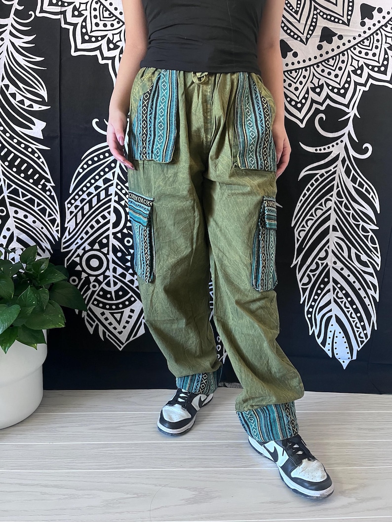 May include: Green cargo pants with blue and white patterned trim around the waist and legs. The pants have large pockets on the sides.