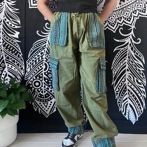 May include: Green cargo pants with blue and green patterned fabric accents on the pockets and cuffs. The pants have a relaxed fit and are made of a lightweight fabric.