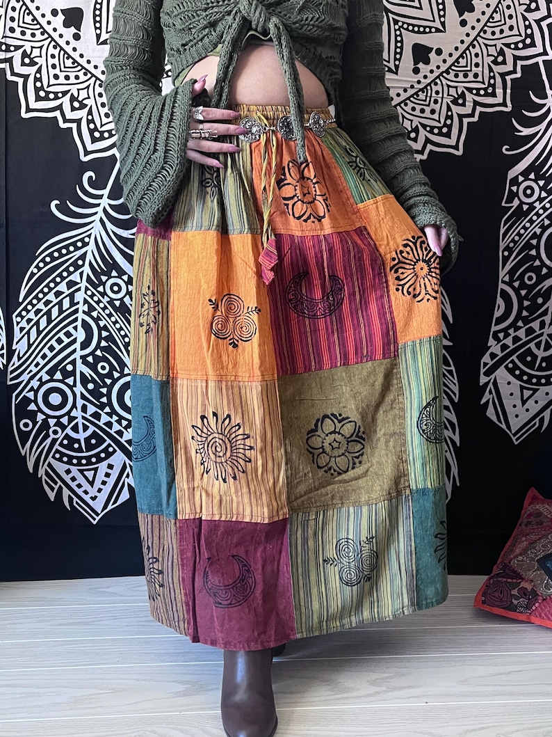 Puede incluir: Una falda larga de retazos multicolor con una variedad de dise&ntilde;os impresos. La falda est&aacute; hecha de algod&oacute;n y tiene un corte holgado. La falda es una mezcla vibrante de naranja, rojo, verde y marr&oacute;n.