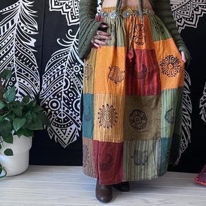 Puede incluir: Una falda larga de estilo bohemio con parches de varios colores. La falda est&aacute; hecha de diferentes telas y tiene una variedad de patrones, incluyendo c&iacute;rculos, espirales y rayas. La falda est&aacute; ce&ntilde;ida a la cintura con un cintur&oacute;n plateado.