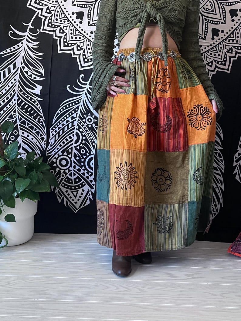 Puede incluir: Una falda larga de estilo bohemio con parches de varios colores. La falda est&aacute; hecha de diferentes telas y tiene una variedad de patrones, incluyendo c&iacute;rculos, espirales y rayas. La falda est&aacute; ce&ntilde;ida a la cintura con un cintur&oacute;n plateado.