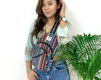 May include: A colourful striped and patterned crossbody bag with a black strap. The bag has multiple pockets and zippers.