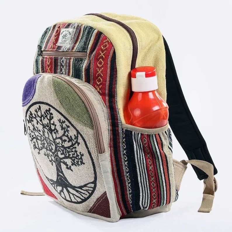 May include: A multi-colored canvas backpack with a tree of life design. The backpack has a side pocket with a red water bottle inside.