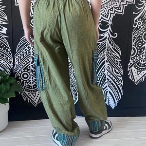 May include: Green cargo pants with a drawstring waist and embroidered details on the legs and cuffs.