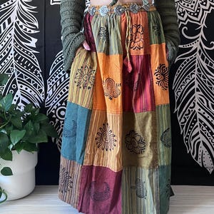 Puede incluir: Una falda larga de patchwork multicolor con una variedad de dise&ntilde;os impresos, incluyendo lunas, soles y flores. La falda est&aacute; hecha de algod&oacute;n y tiene un estilo bohemio.