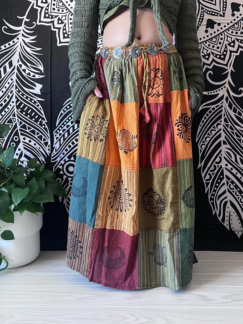 Puede incluir: Una falda larga de patchwork multicolor con una variedad de dise&ntilde;os impresos, incluyendo lunas, soles y flores. La falda est&aacute; hecha de algod&oacute;n y tiene un estilo bohemio.