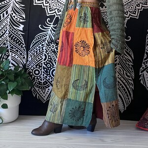 Puede incluir: Una falda larga de retazos multicolor con una abertura delantera. La falda presenta una variedad de patrones, incluyendo lunas, estrellas y flores. La falda est&aacute; hecha de una tela suave y fluida y tiene un estilo bohemio.