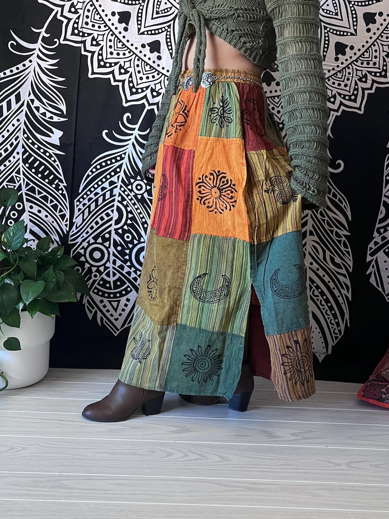 Puede incluir: Una falda larga de retazos multicolor con una abertura delantera. La falda presenta una variedad de patrones, incluyendo lunas, estrellas y flores. La falda est&aacute; hecha de una tela suave y fluida y tiene un estilo bohemio.