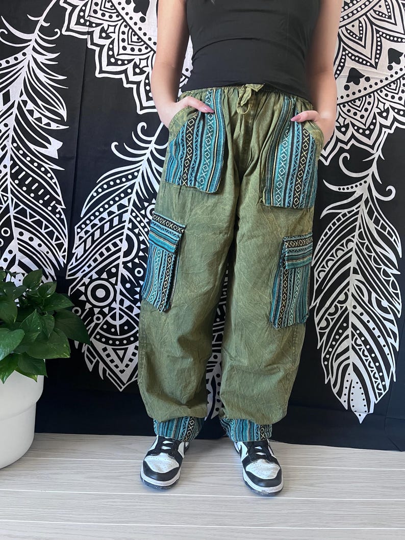 May include: Green cargo pants with blue and white patterned fabric accents on the pockets and cuffs. The pants have a drawstring waist and are worn with black sneakers.