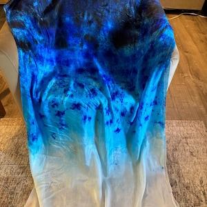 May include: A blue and white ombre tie-dye fabric with a dark blue and black pattern at the top.