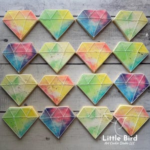May include: A collection of diamond-shaped cookies with a watercolor effect. Each cookie features a different color gradient, including yellow, green, blue, and pink, outlined with white icing. The cookies are arranged on a light wooden surface.